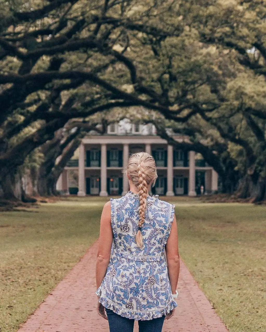Blonde woman walking up oak lined walkway at Oak Alley Plantation in New Orleans, Louisiana