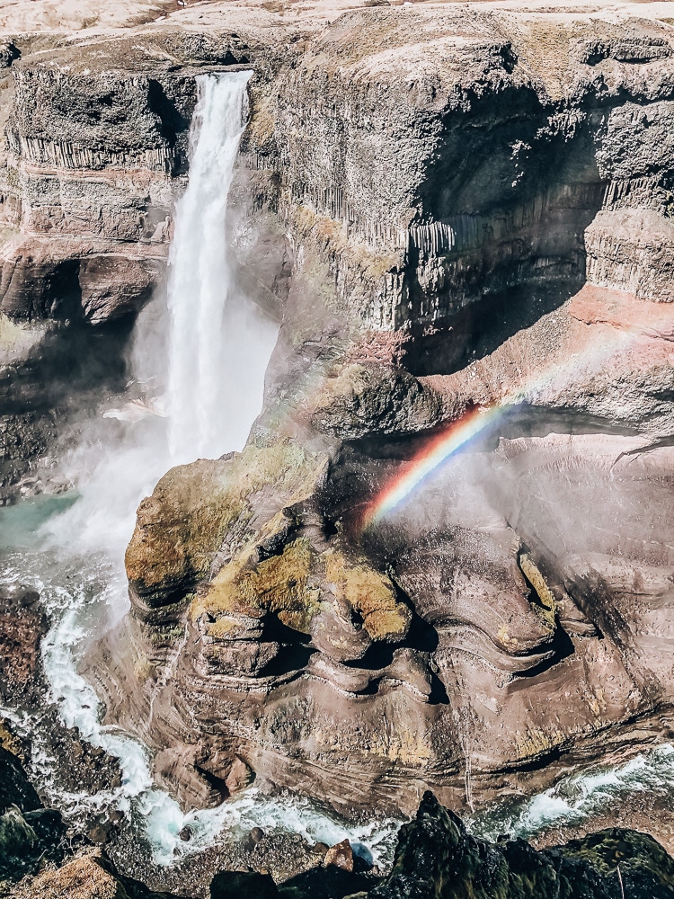 Haifoss waterfall with a rainbow in the mist in Iceland. Find the top 5 waterfalls in Iceland that you don't want to miss on a Ring Road road trip. 
