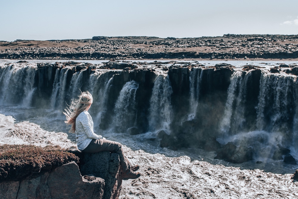 Sitting on the edge of the canyon looking at Selfoss Waterfall in Northern Iceland. Find the top 5 waterfalls in Iceland that you don't want to miss on a Ring Road road trip. 