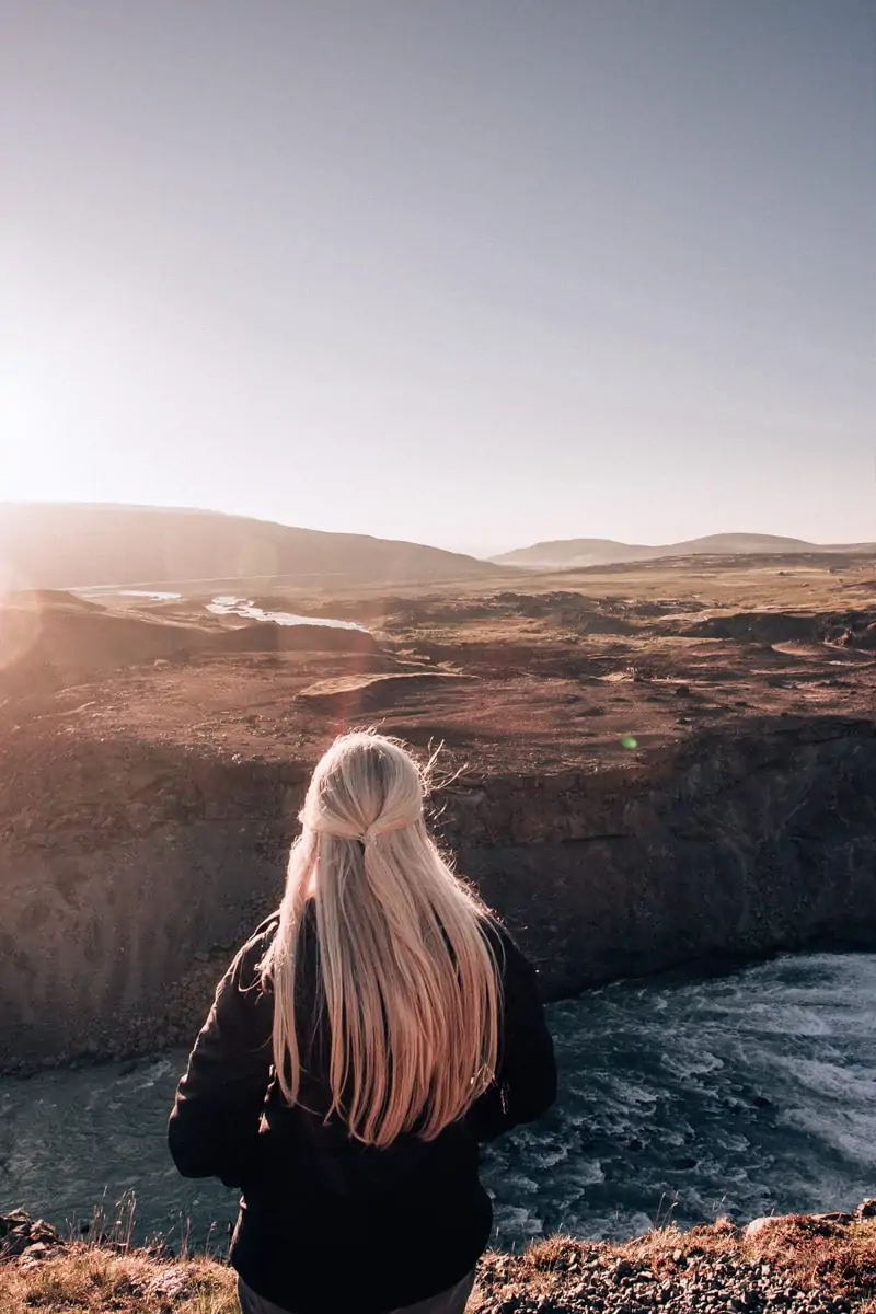 A woman watches sunset over the landscape near Aldeyjarfoss in Iceland. Find the best itinerary for summer in Iceland full of Iceland travel tips here.