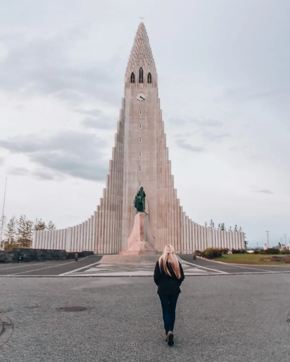 Woman walking up to Hallgrimskirkja church in Reykjavik. Get a full Iceland travel guide with itinerary and map here.
