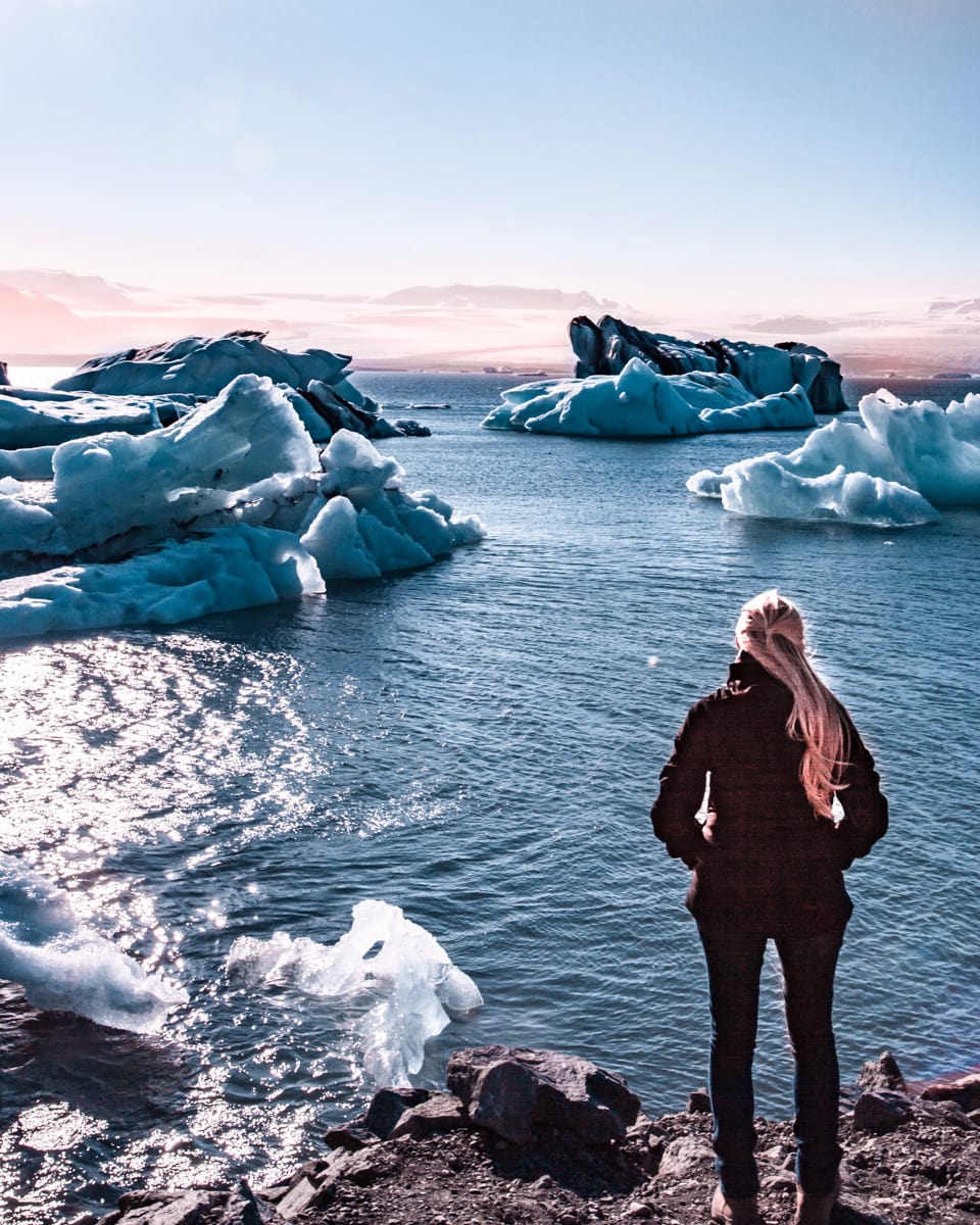 Standing at the edge of Jokulsarlon Glacier Lagoon in Iceland in summer near sunset. Get all the best Iceland photo locations and Iceland travel tips in our ultimate 6 day Iceland itinerary.