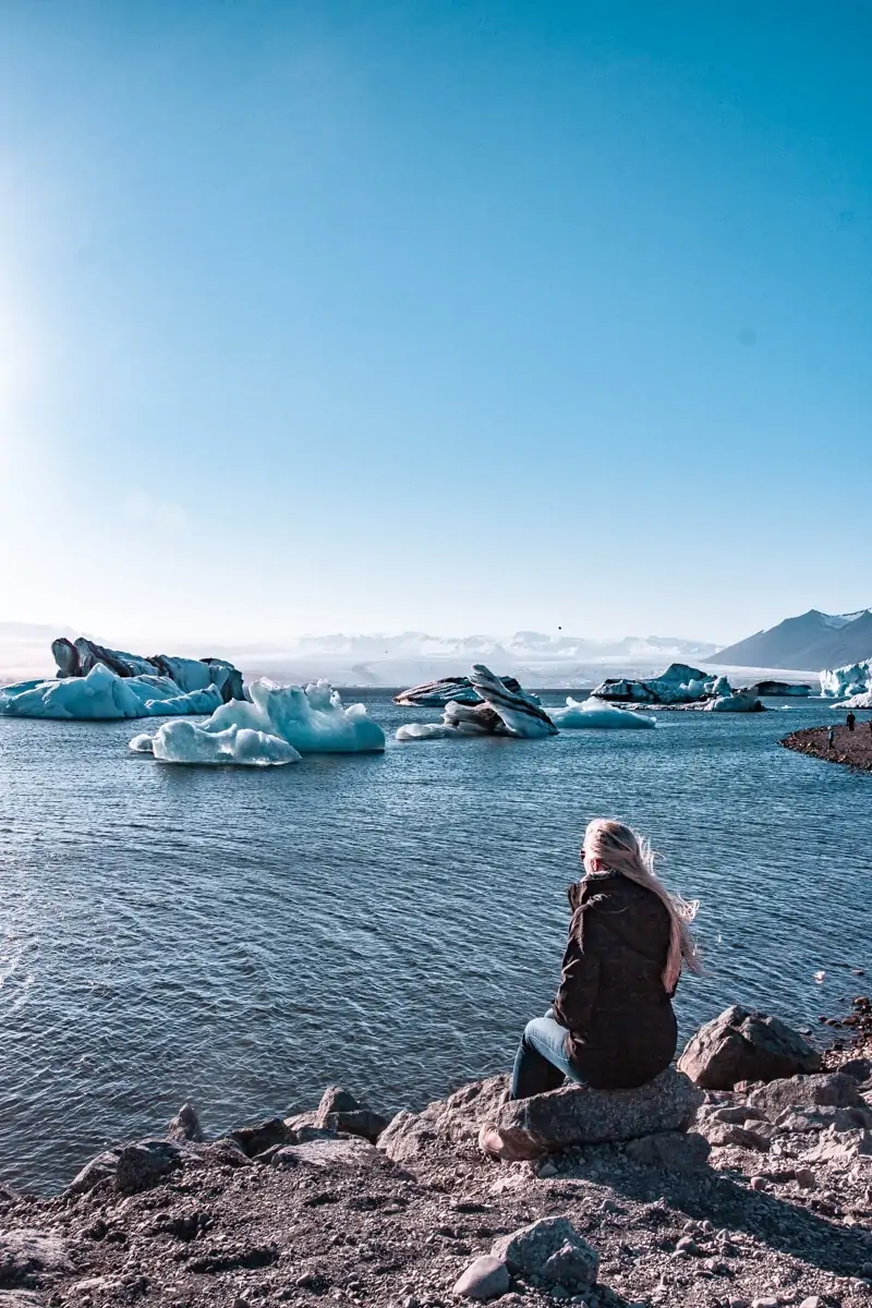 Sitting on the edge of Jokulsarlon Glacier Lagoon in Iceland during summer. Click here for a 6 day Iceland itinerary full of all of Iceland's best travel tips.