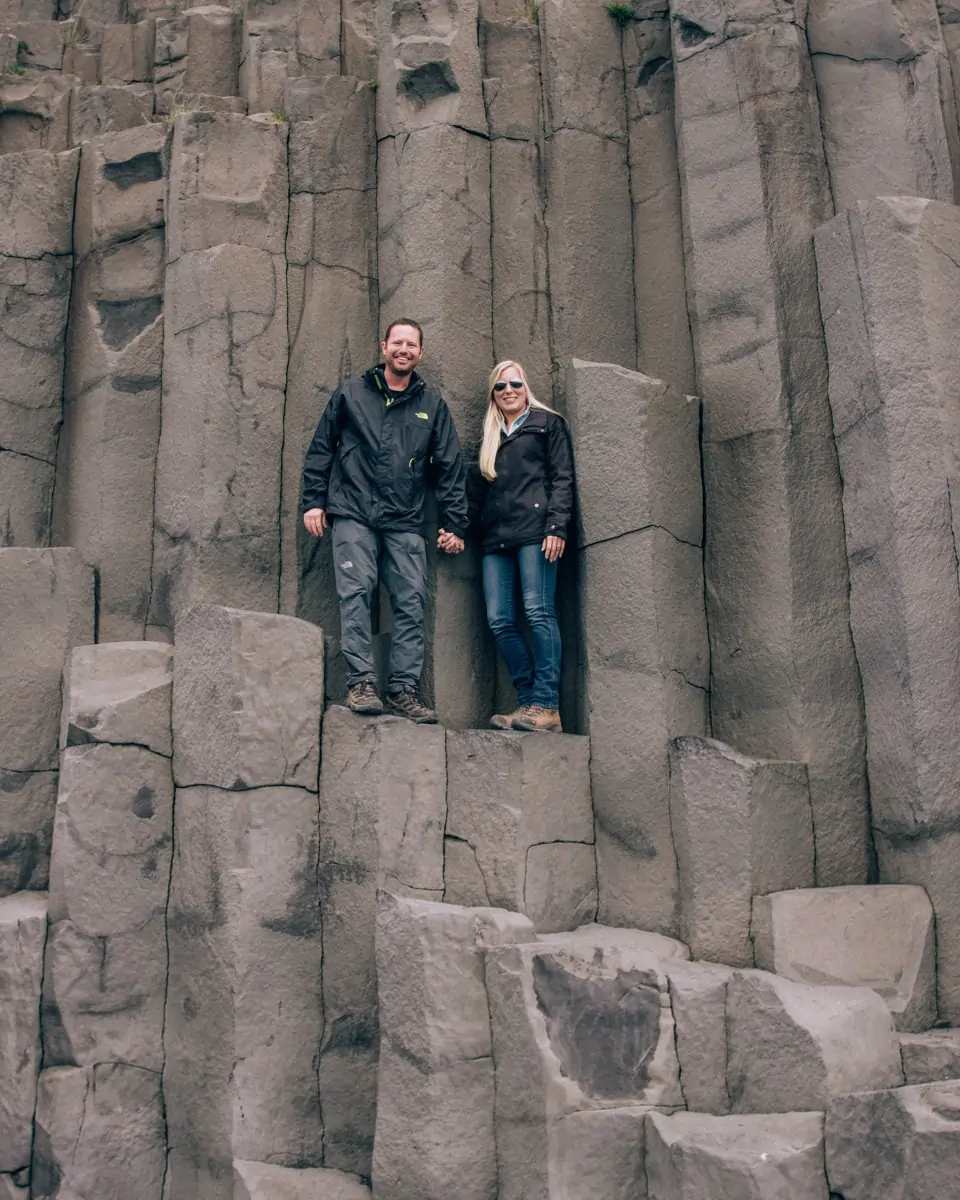 Couple standing on the Basalt columns at Reynisfajara Beach near Vik in Iceland. Get our full Iceland travel guide including the best photo spots in Iceland in our 6 day Iceland itinerary.