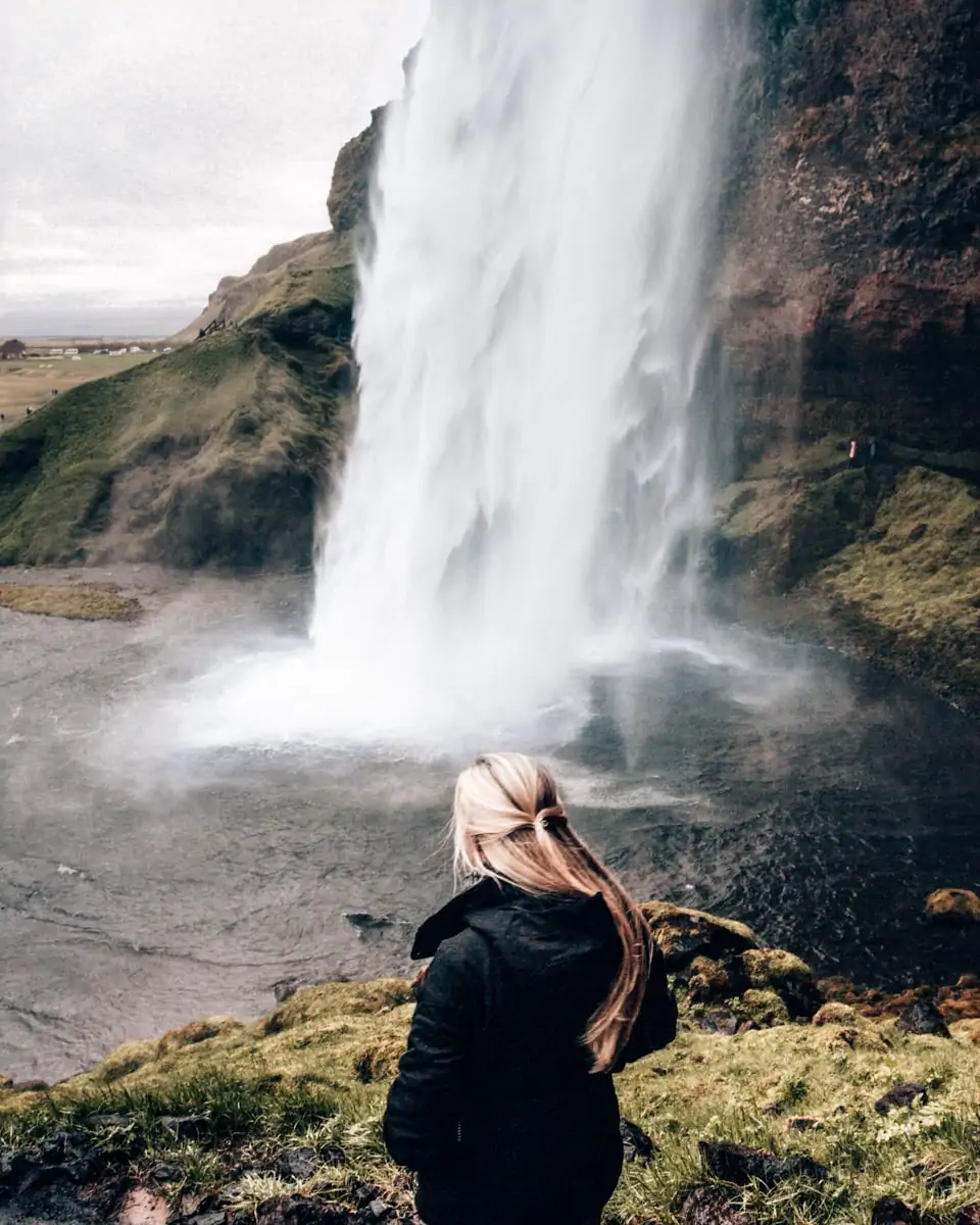 Standing on the path that takes you behind Seljalandsfoss waterfall in Iceland. Get a full 6 day itinerary for Iceland here!