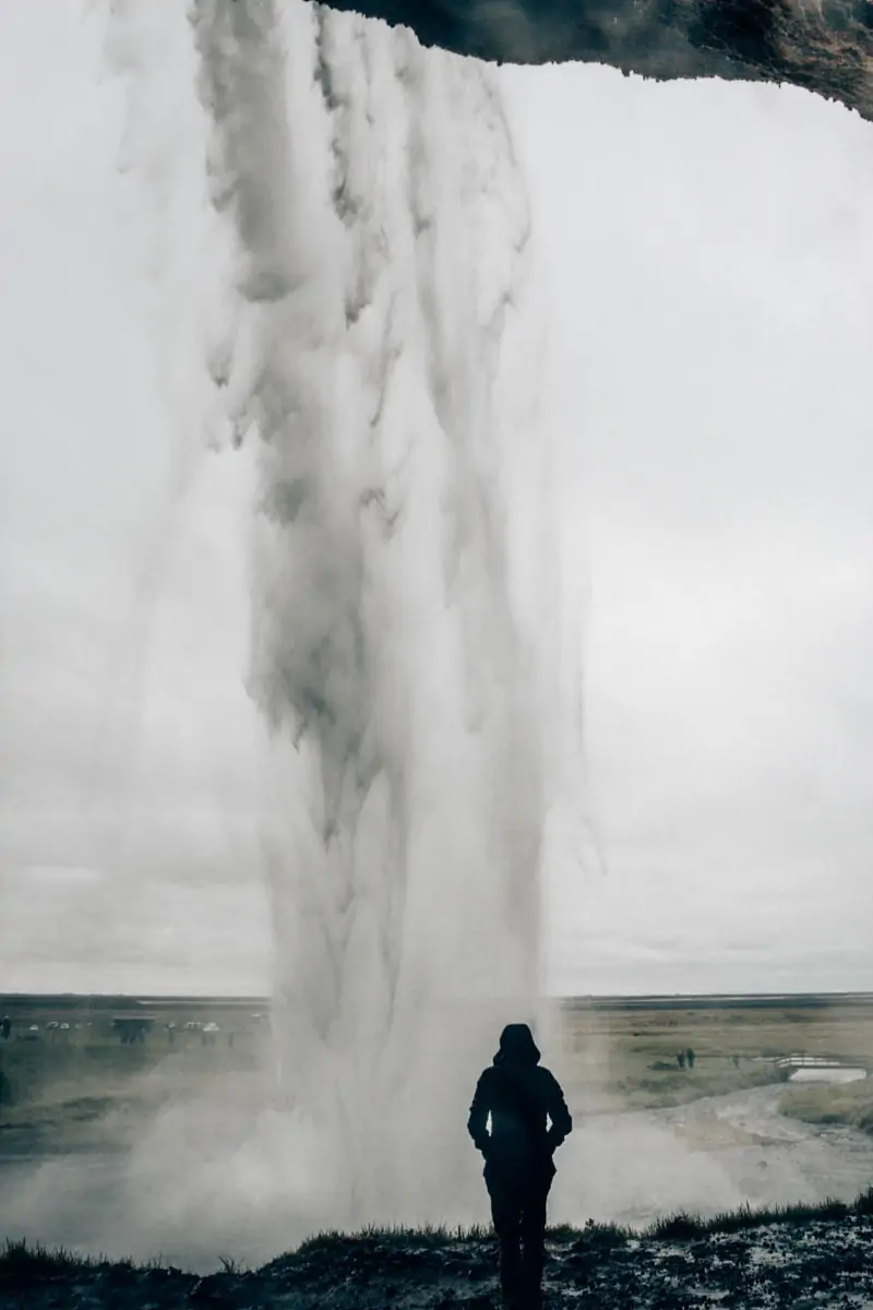 Standing behind Seljalandsfoss Waterfall in Iceland and getting soaked by the mist. Find a full road trip itinerary for summer in Iceland here.