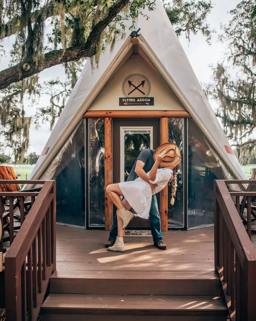 Couple glamping in Florida in front of a Westgate River Ranch teepee with cowboy hat and boots