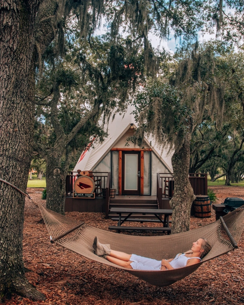 Relaxing in a hammock outside of a luxe teepee at Westgate River Ranch, one of the best places to go glamping in Florida..