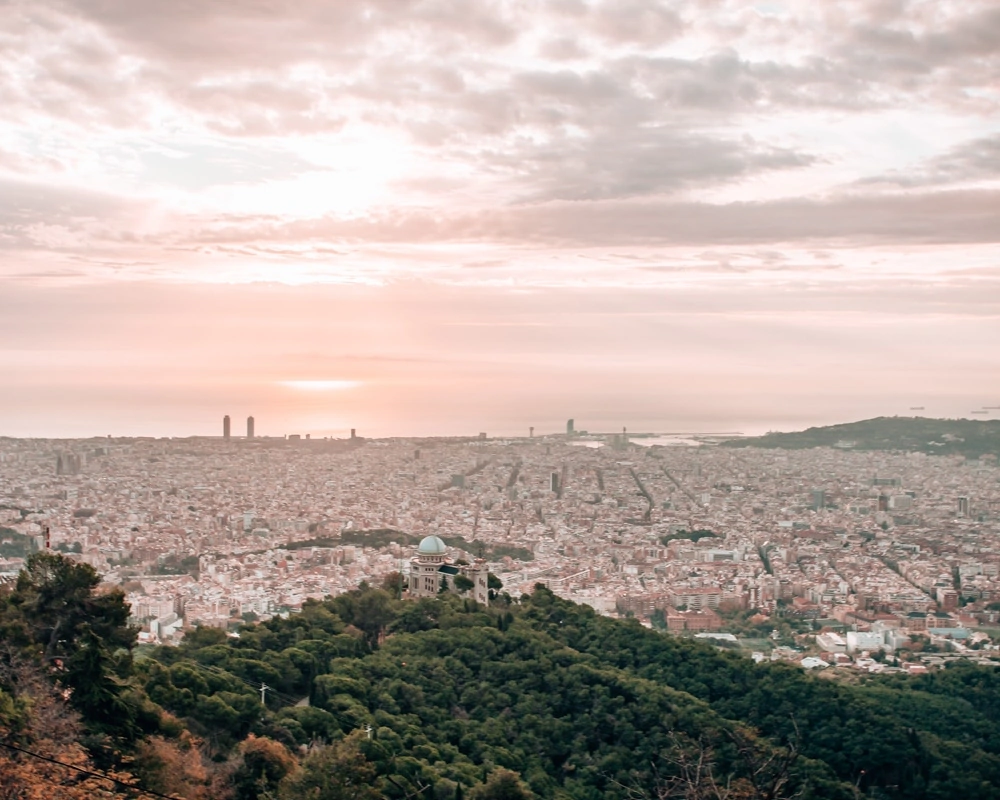 The view of the city of Barcelona from Mount Tibidabo at sunrise. Click here to find the best views and photo spots in Barcelona and an itinerary to see them all in 3 days.