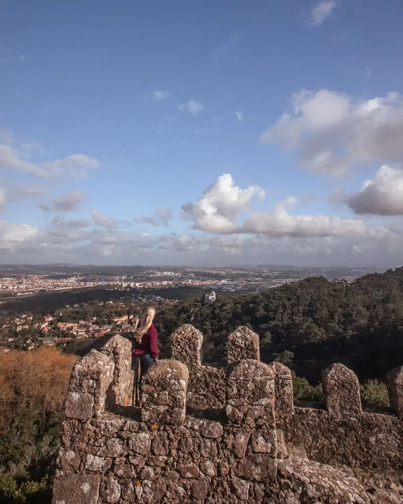 A woman stands on the tower at the Moorish Castle in Sintra