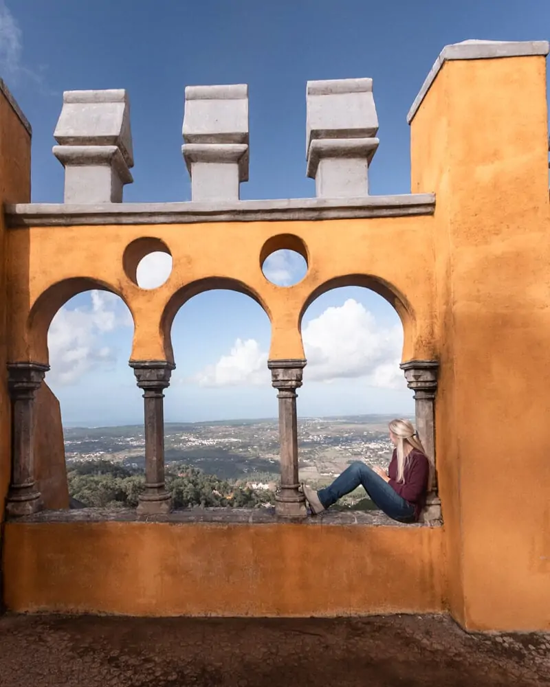 A woman sits in the windows at Pena Palace looking over Sintra