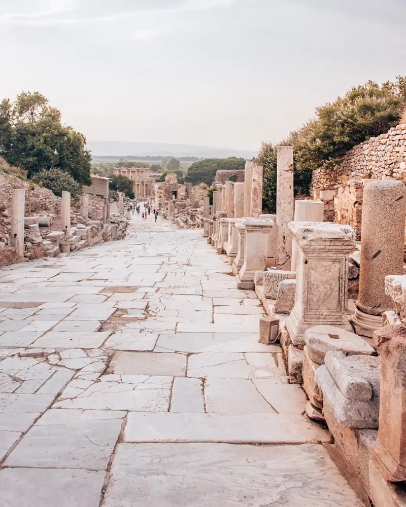 Looking down Curetes Street in Ephesus towards the Library of Celsus. Find a full one day itinerary with everything you need to know about visiting the ancient ruins of Ephesus in Turkey here.