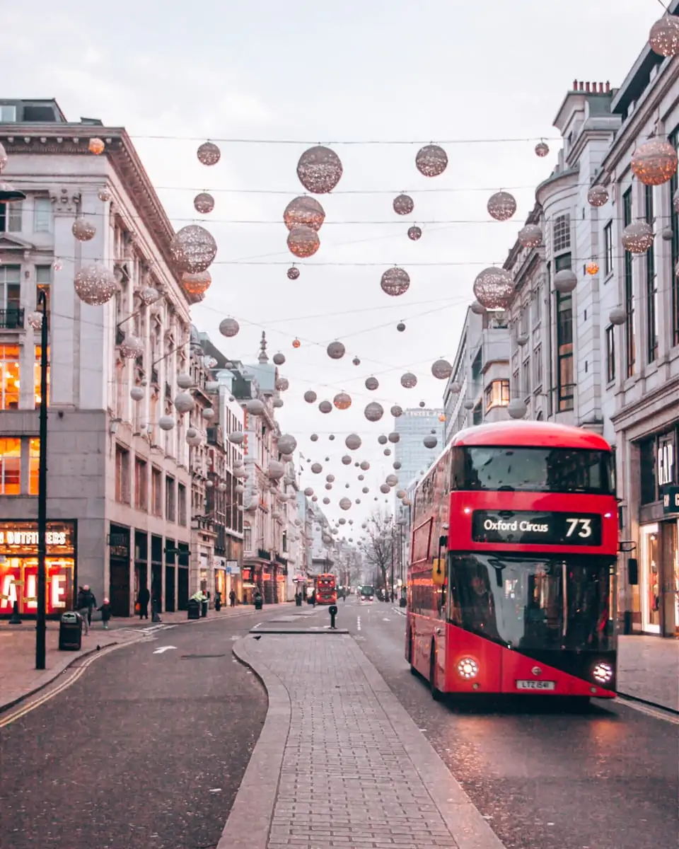 Oxford Street Christmas lights with a double decker bus in London near sunrise.
