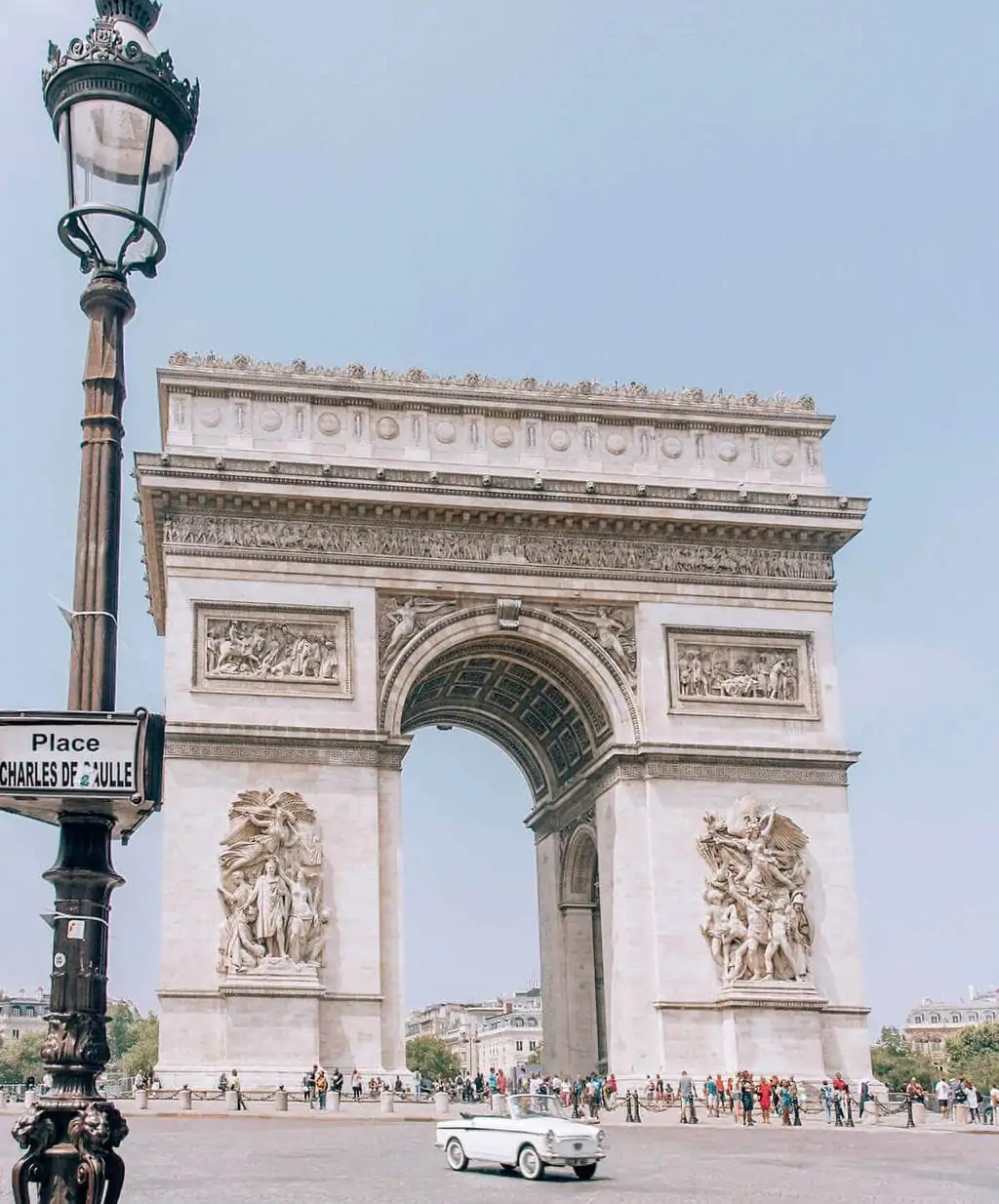 An old car drives past the Arc de Triomphe in Paris. Find lots of Paris travel tips in this guide to Paris at New Year's.