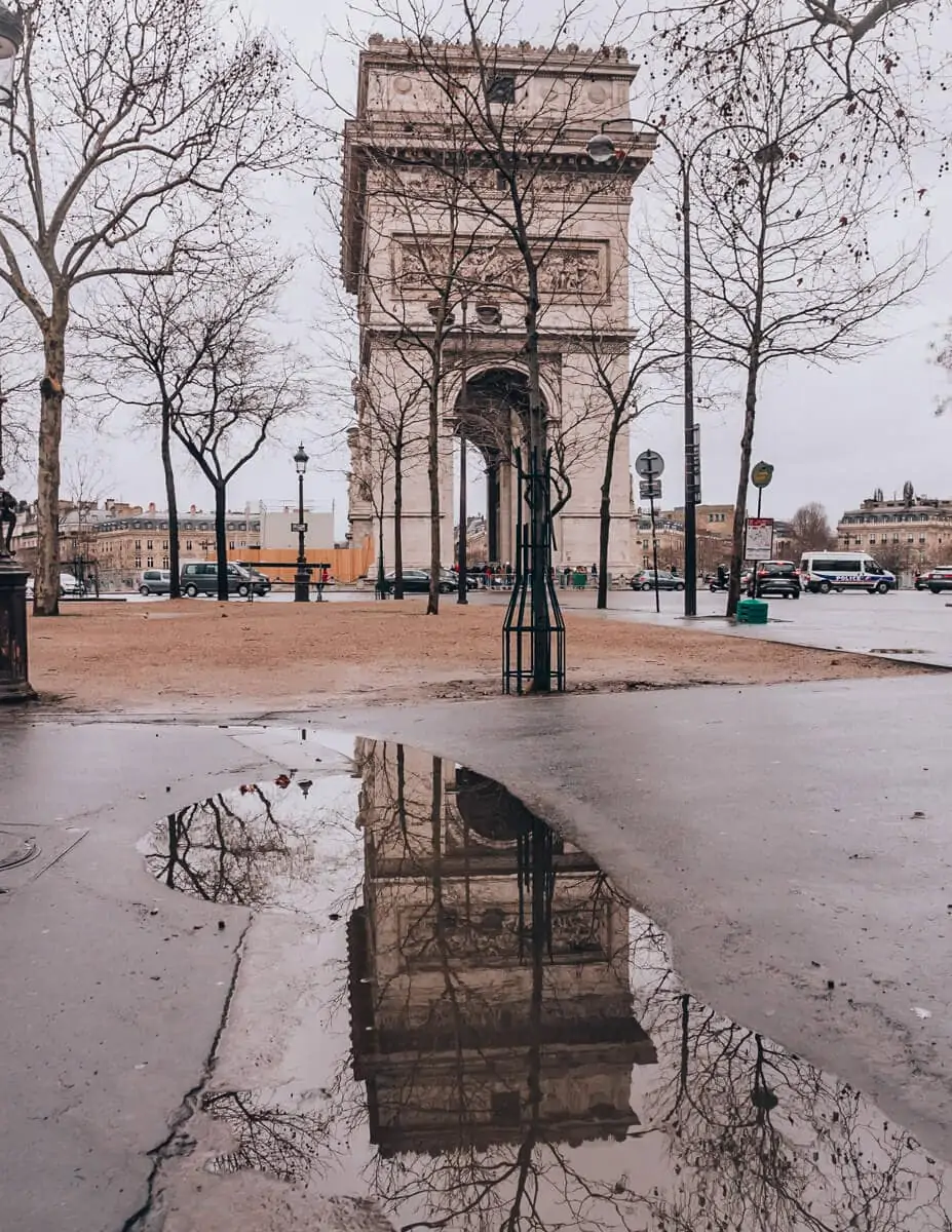 A reflection photo of the Arc de Triomphe in a puddle. Find travel tips for winter in Paris in this guide to New Year's in Paris.