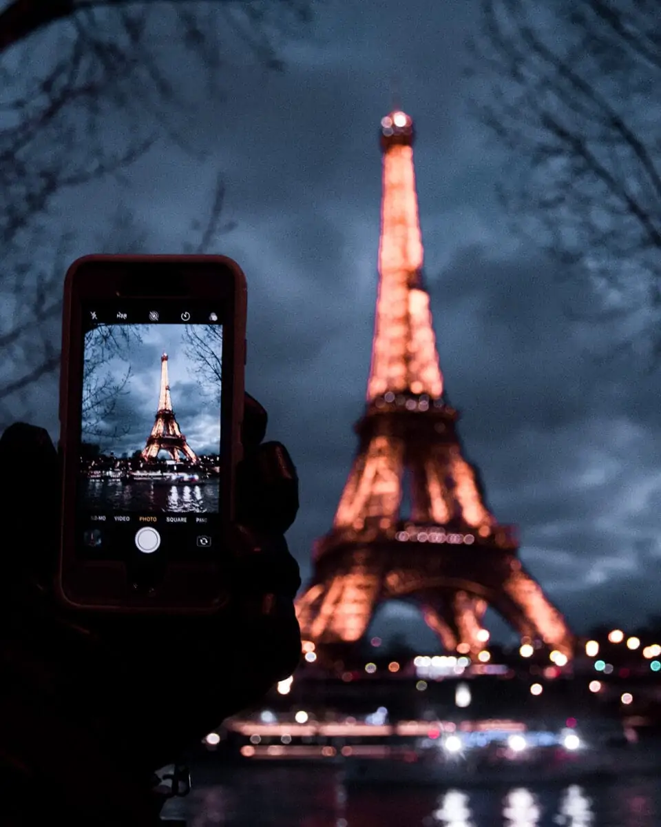 Taking a picture of the Eiffel Tower at night from the Seine river. Find the best Eiffel Tower photo spots and the best ways to celebrate New Year's in Paris here.