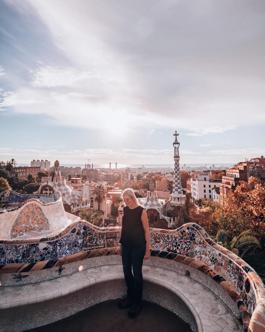 A woman stands in the Greek Theater or Nature Square in Park Guell Barcelona. Free entry gets you in before the crowds.