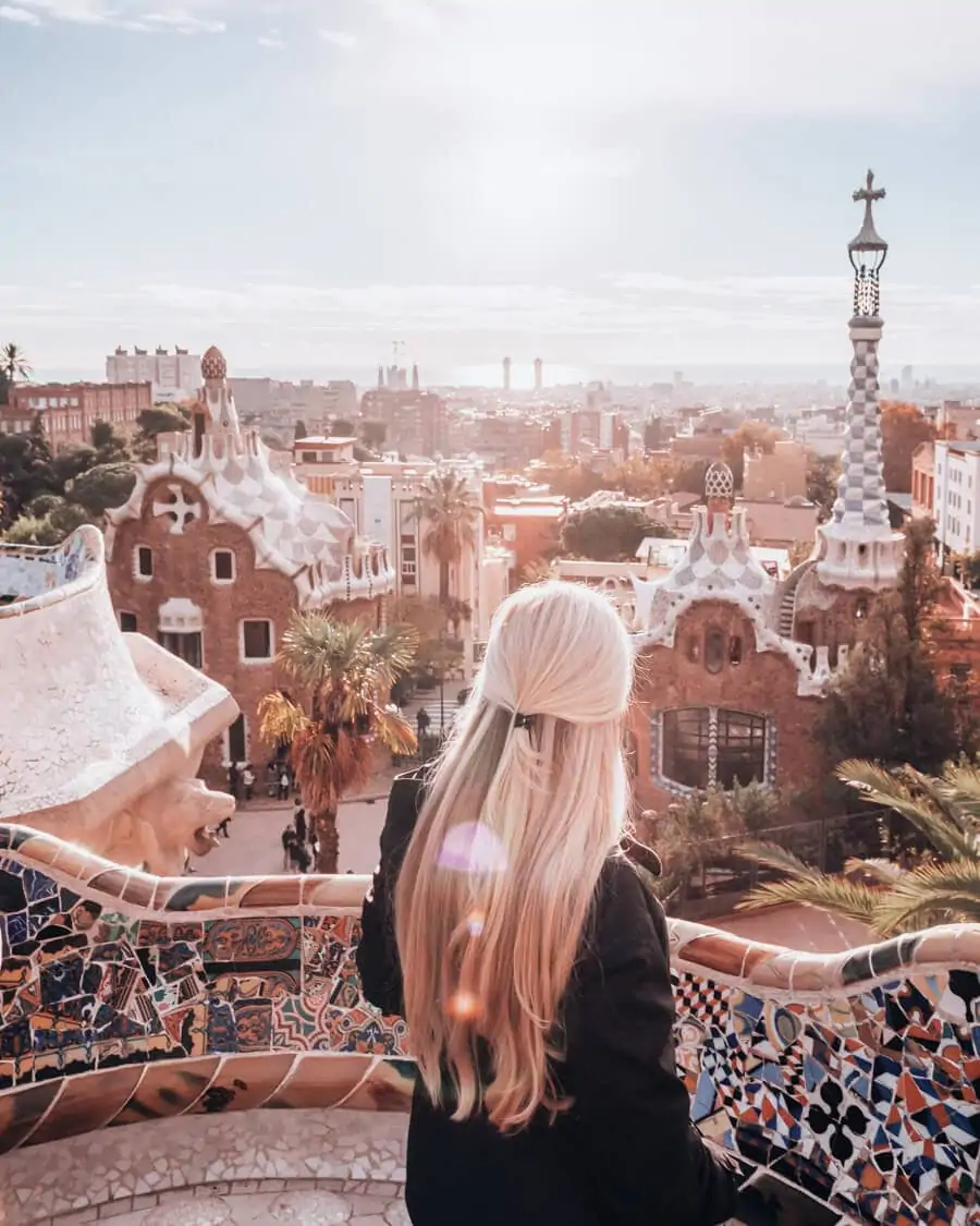 A woman poses in Park Guell Barcelona at sunrise in the Greek Theater.