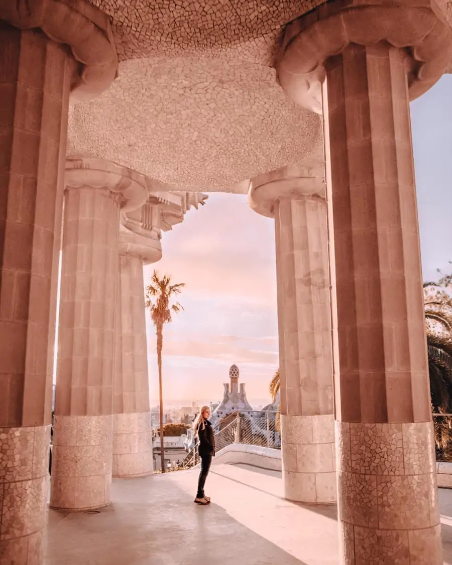 A woman standing among the columns of the Park Guell Hypostyle Room