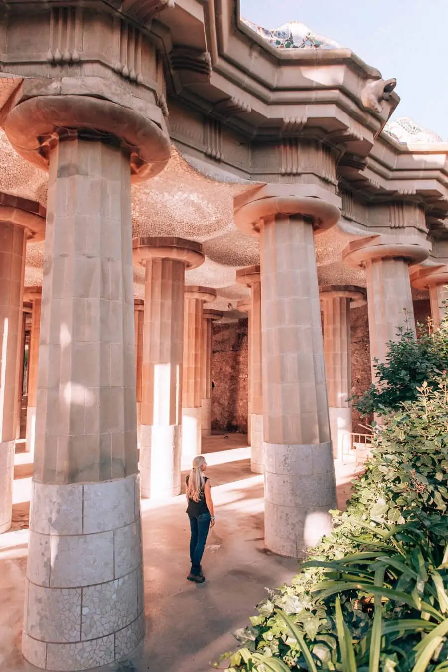 A woman standing in the Hypostyle Room in Park Guell surrounded by columns