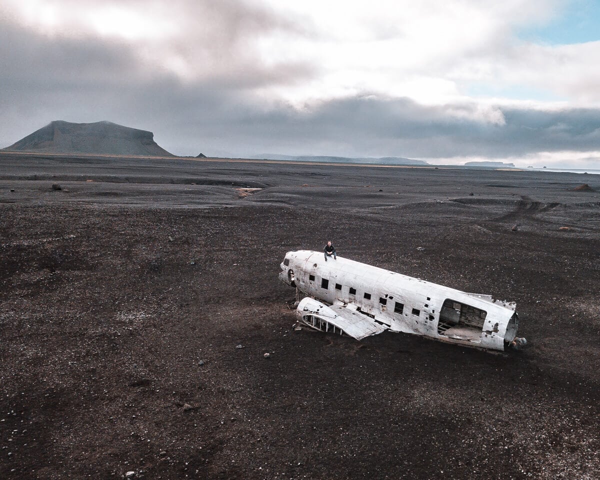 A drone shot of a man on top of the Sólheimasandur plane crash