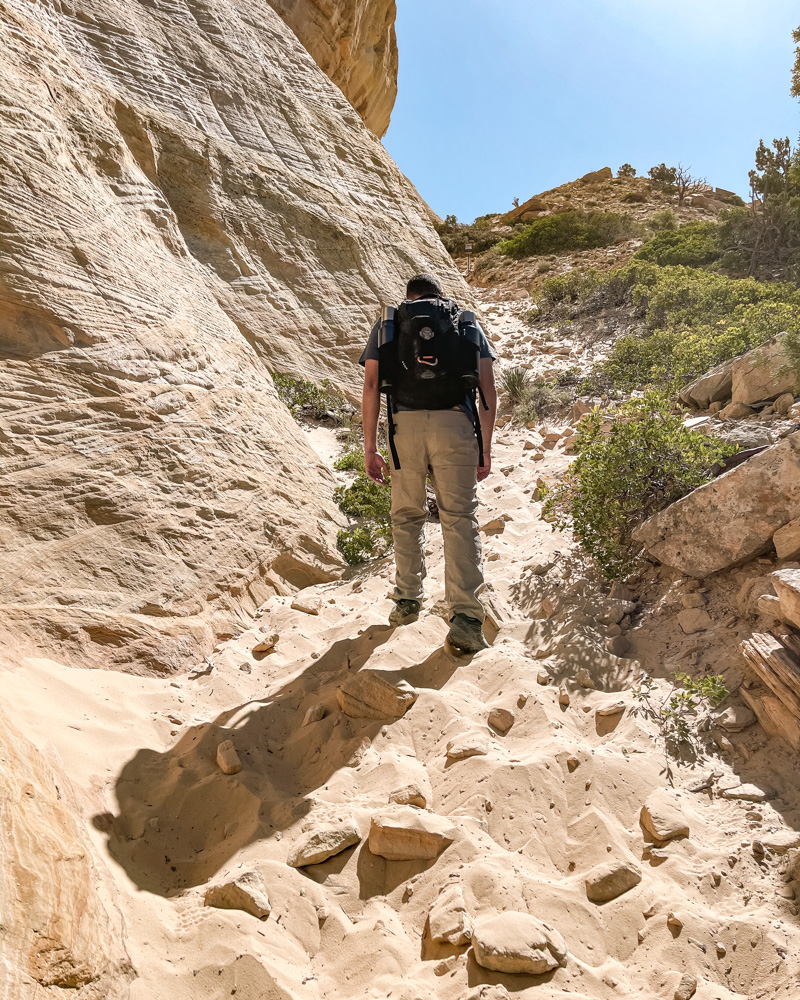 Man hiking to the Great Chamber at Cutler Point in soft sand