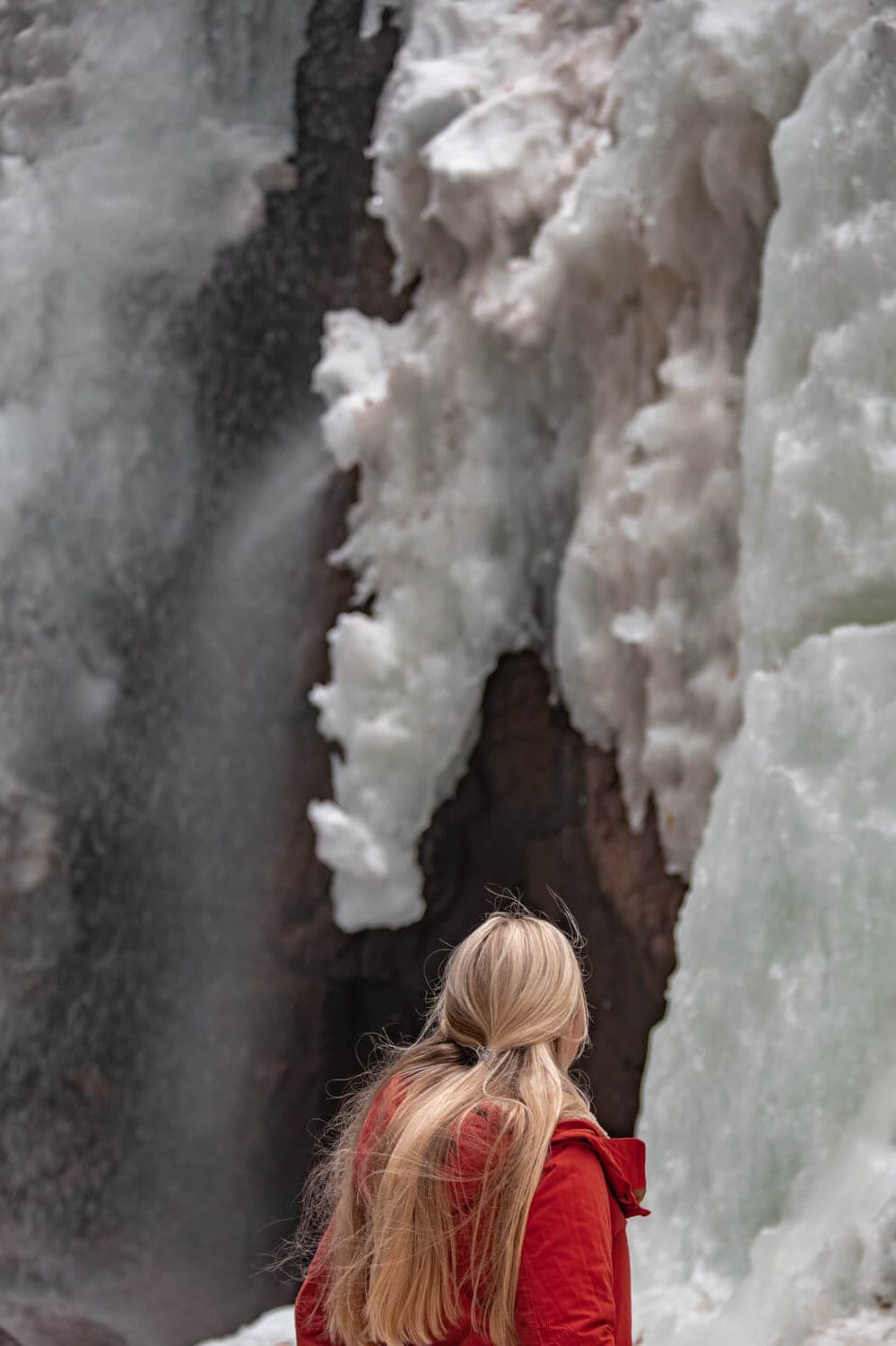 woman in front of champney falls in winter in new hampshire
