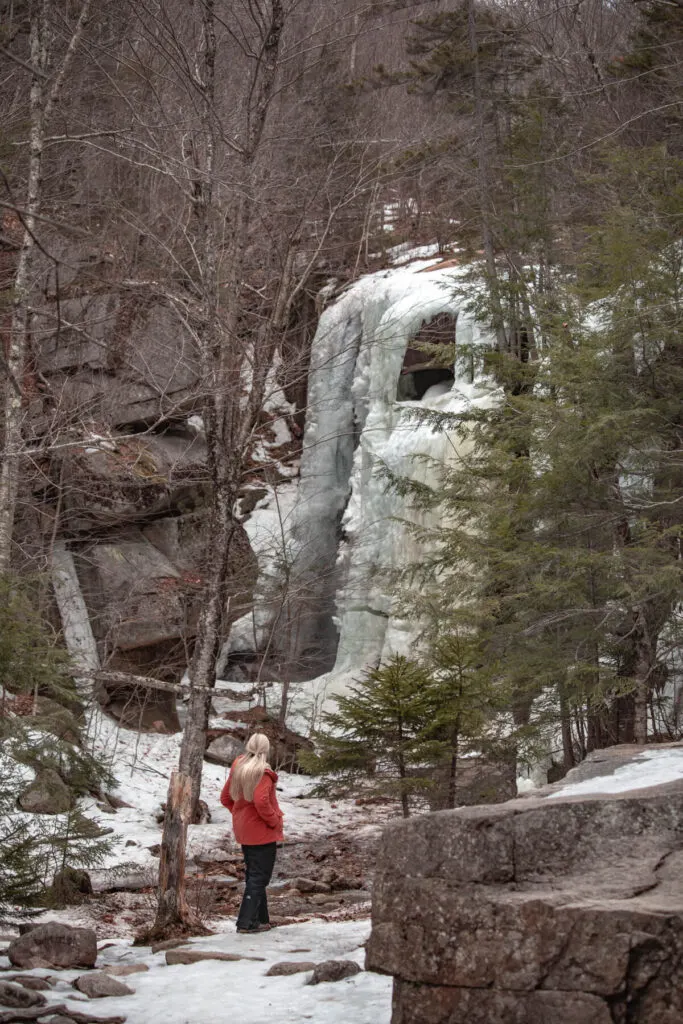 woman in front of frozen champney falls in winter