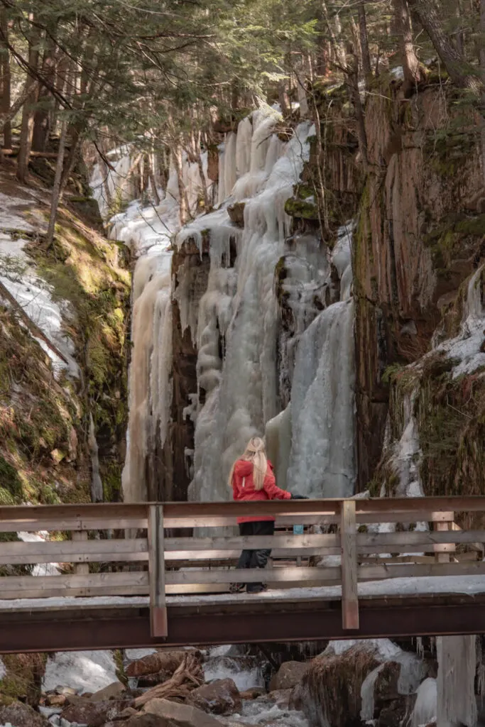 Woman at Avalanche Falls in Flume Gorge in winter