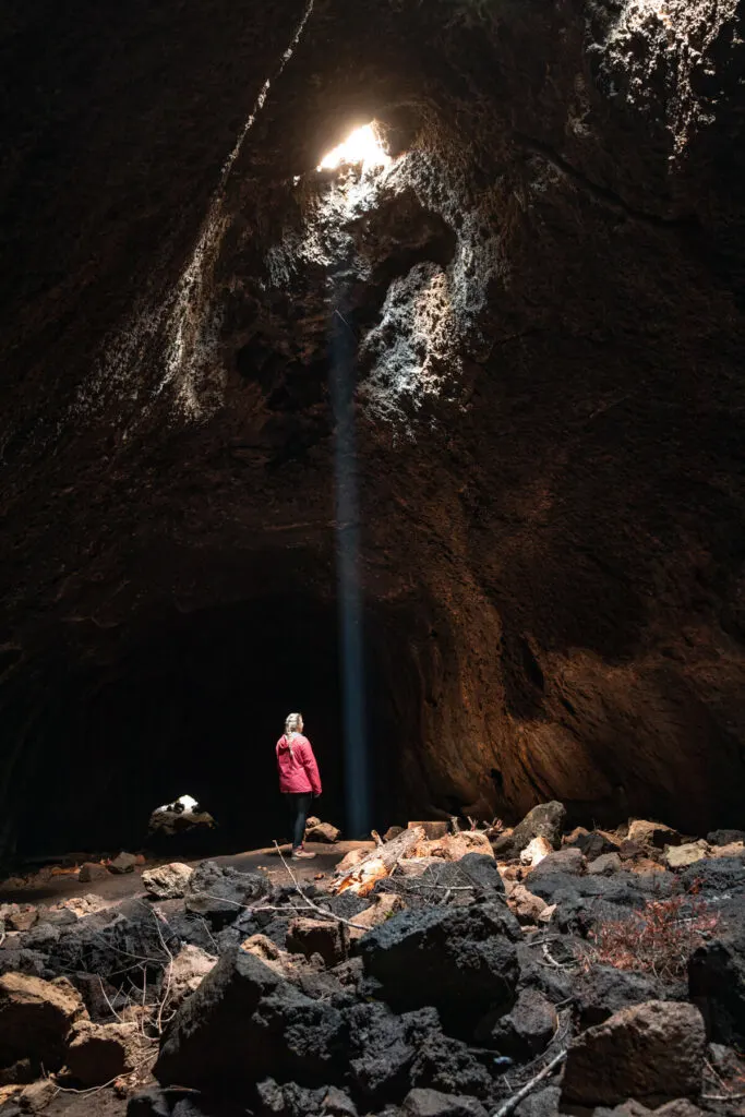 Woman in skylight cave near bend oregon with a single sunbeam