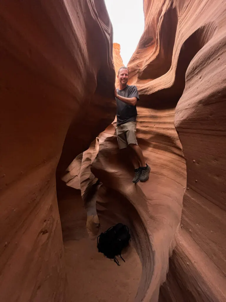 man climbing in southern utah slot canyon