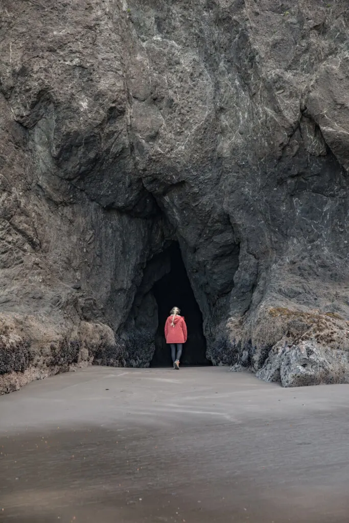 woman walking into sea cave in oregon on secret beach