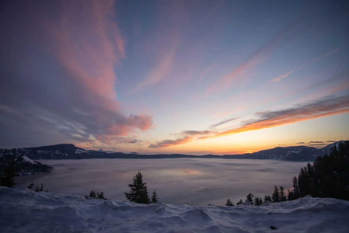 sunrise over crater lake with pastel colored clouds