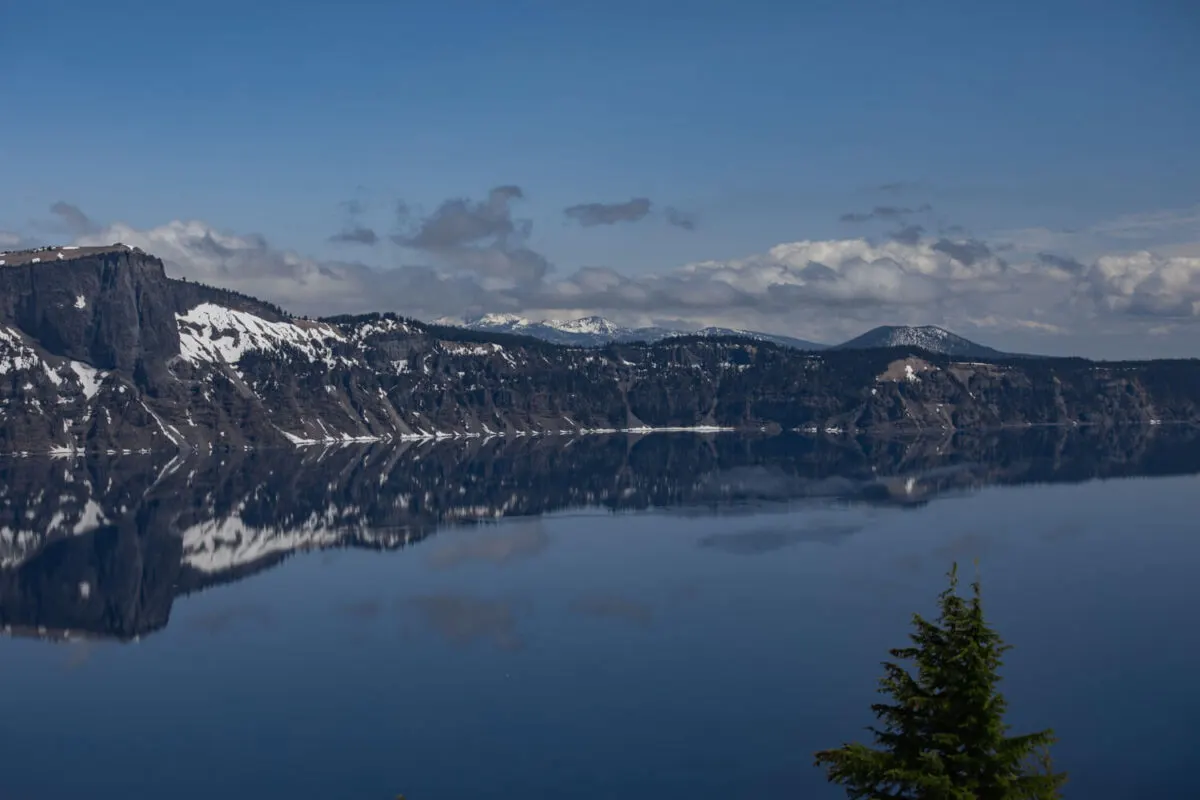 crater lake reflecting the white puffy clouds and blue sky