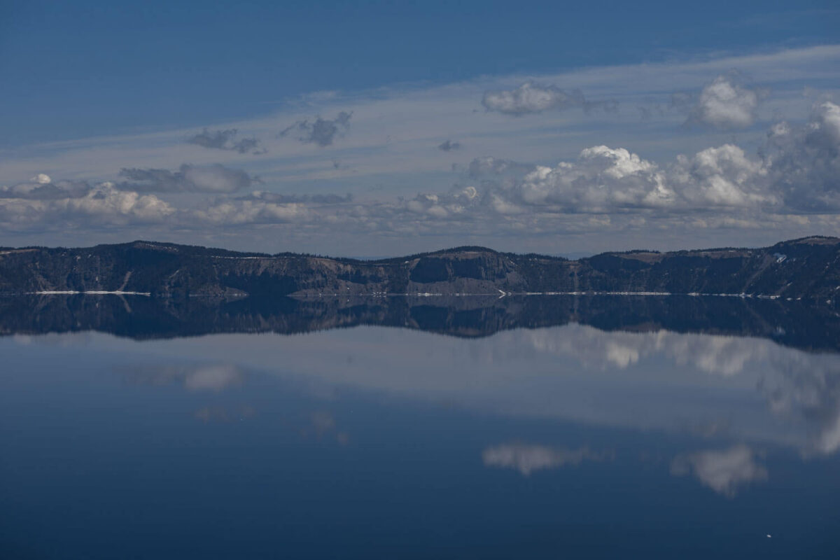 crater lake reflecting the blue sky and white clouds