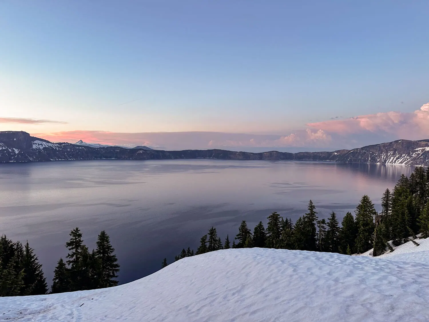 snow and pink clouds as crater lake frosts over at sunset