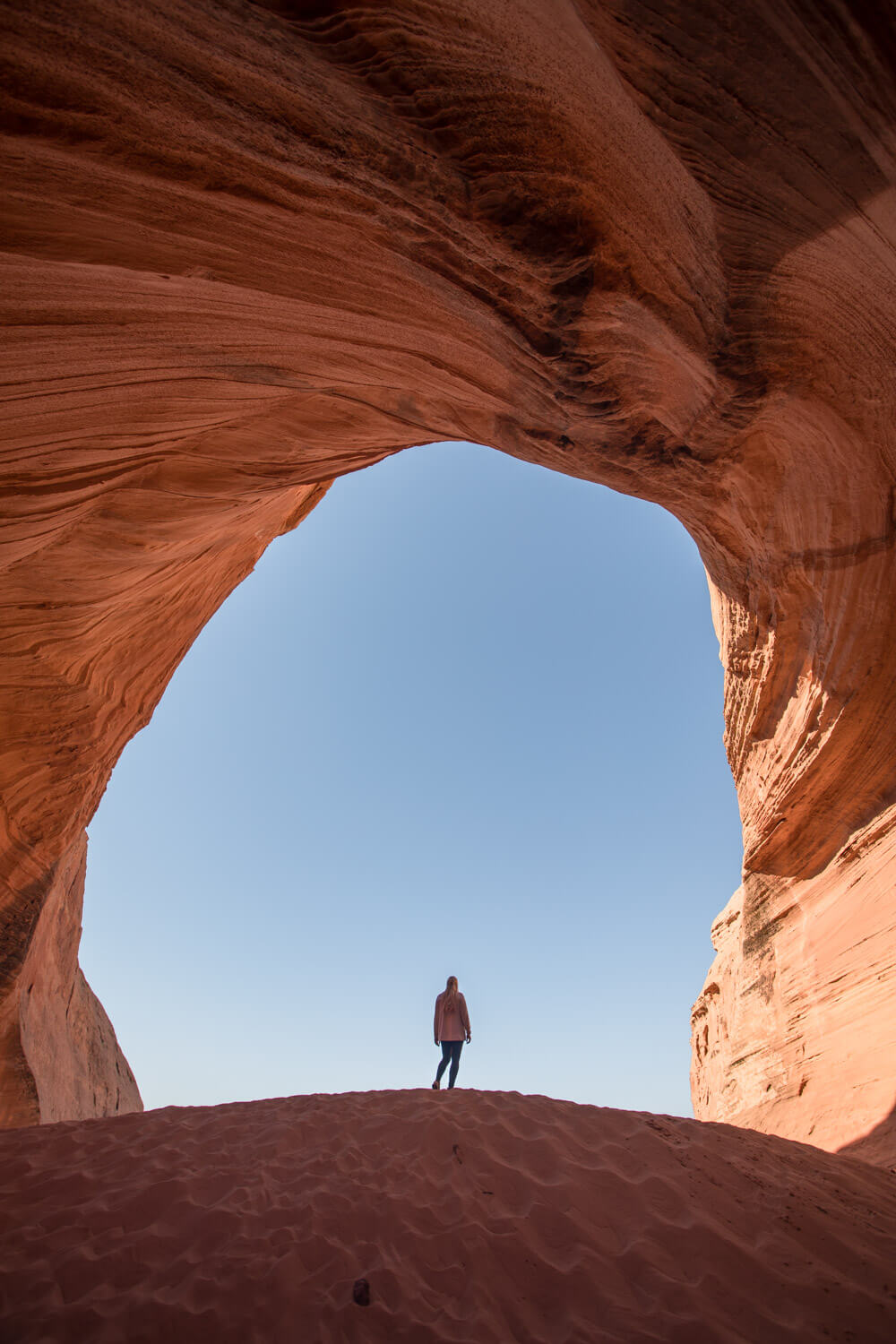 big lake sand cave in page arizona with a woman standing on the sand dune in the cave